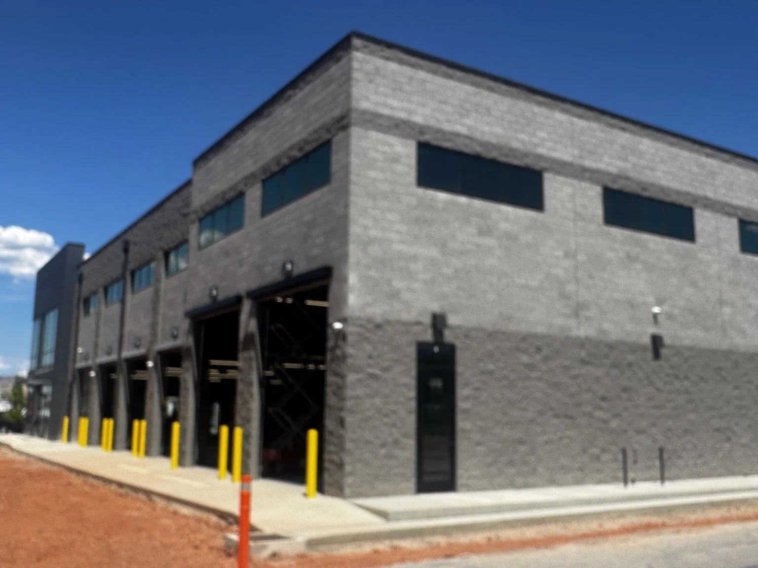 Close view of the Big O Tire service-bay facade, finished exterior trim, and bright yellow protective posts