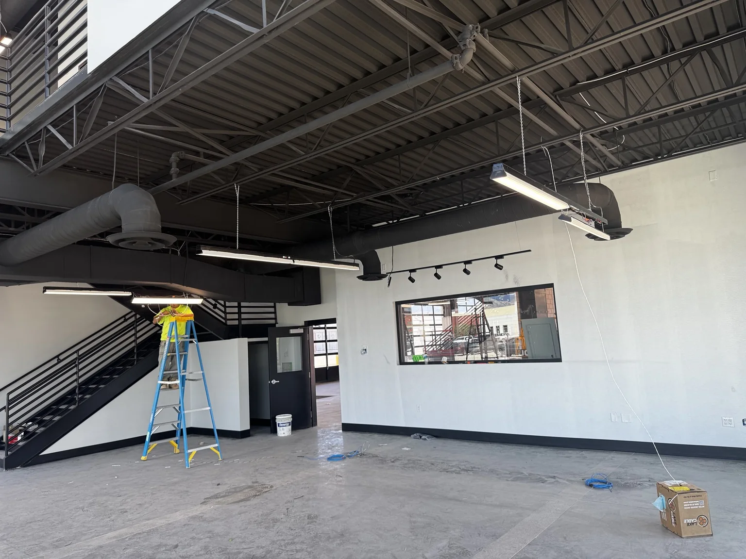 Big O Tire showroom interior with white painted walls, black ceiling and ductwork, and a finished steel staircase
