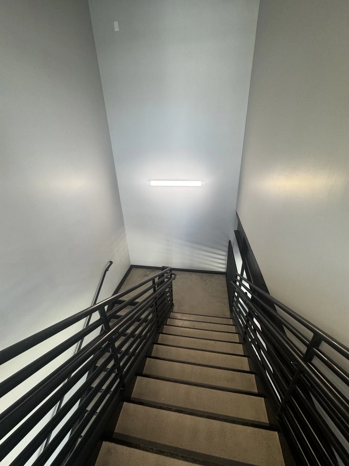 Detailed view of the Big O Tire staircase with light treads, black metal railings, and painted interior walls