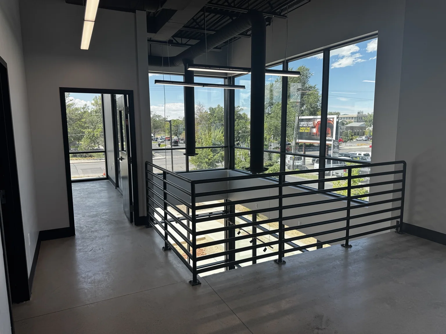 Upper-level Big O Tire mezzanine with black metal railings and large windows overlooking the showroom