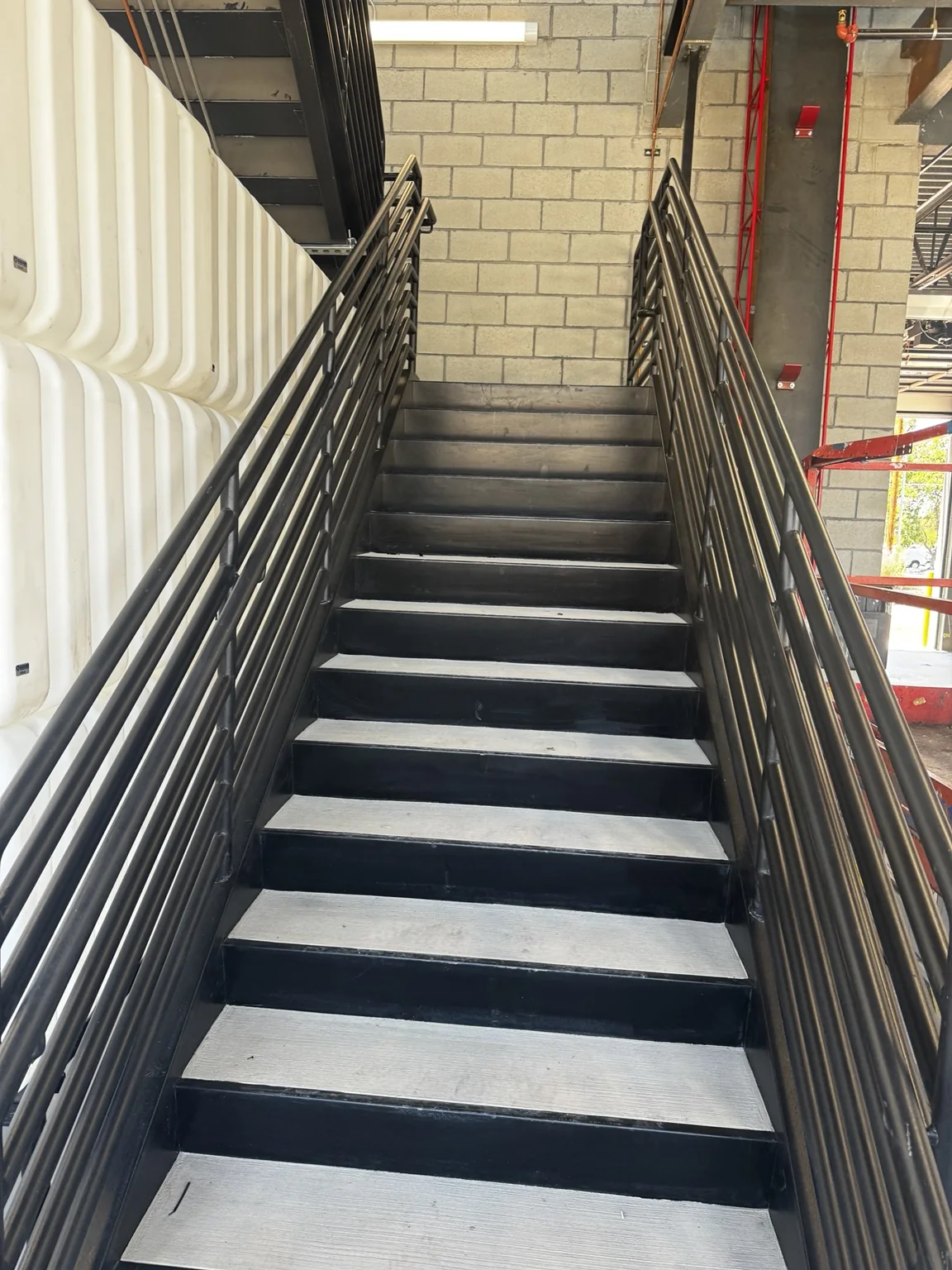 Close-up of a Big O Tire steel staircase with dark painted railings and contrasting light stair treads