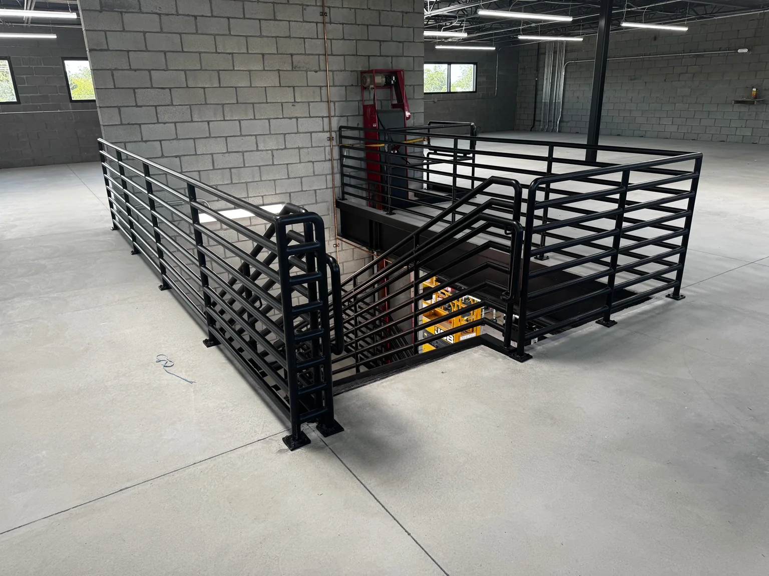 Upper-level Big O Tire mezzanine with a custom black-painted steel guardrail around the stair opening