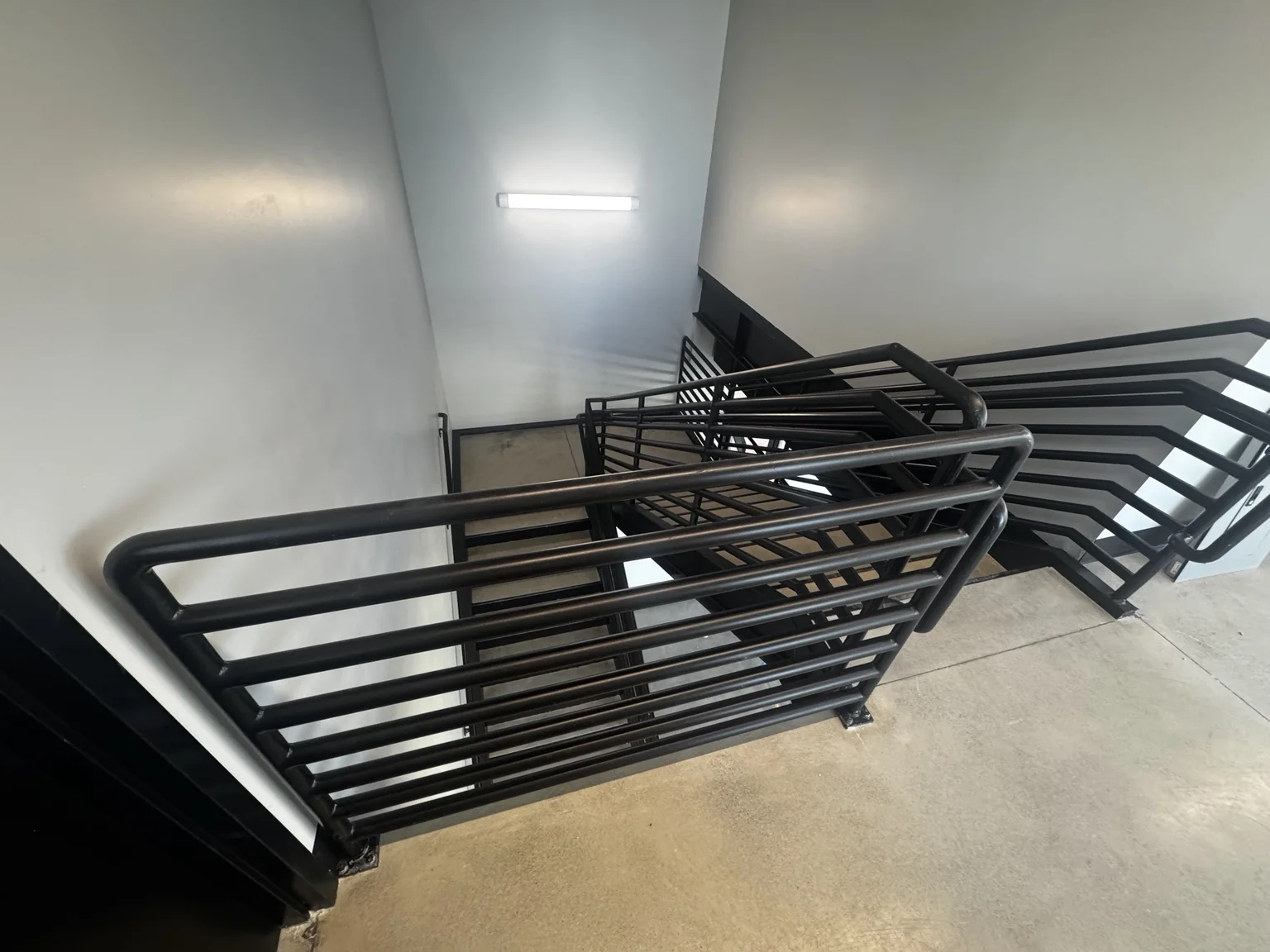 Detailed view of black-painted steel guardrails at a clean white Big O Tire interior stair landing
