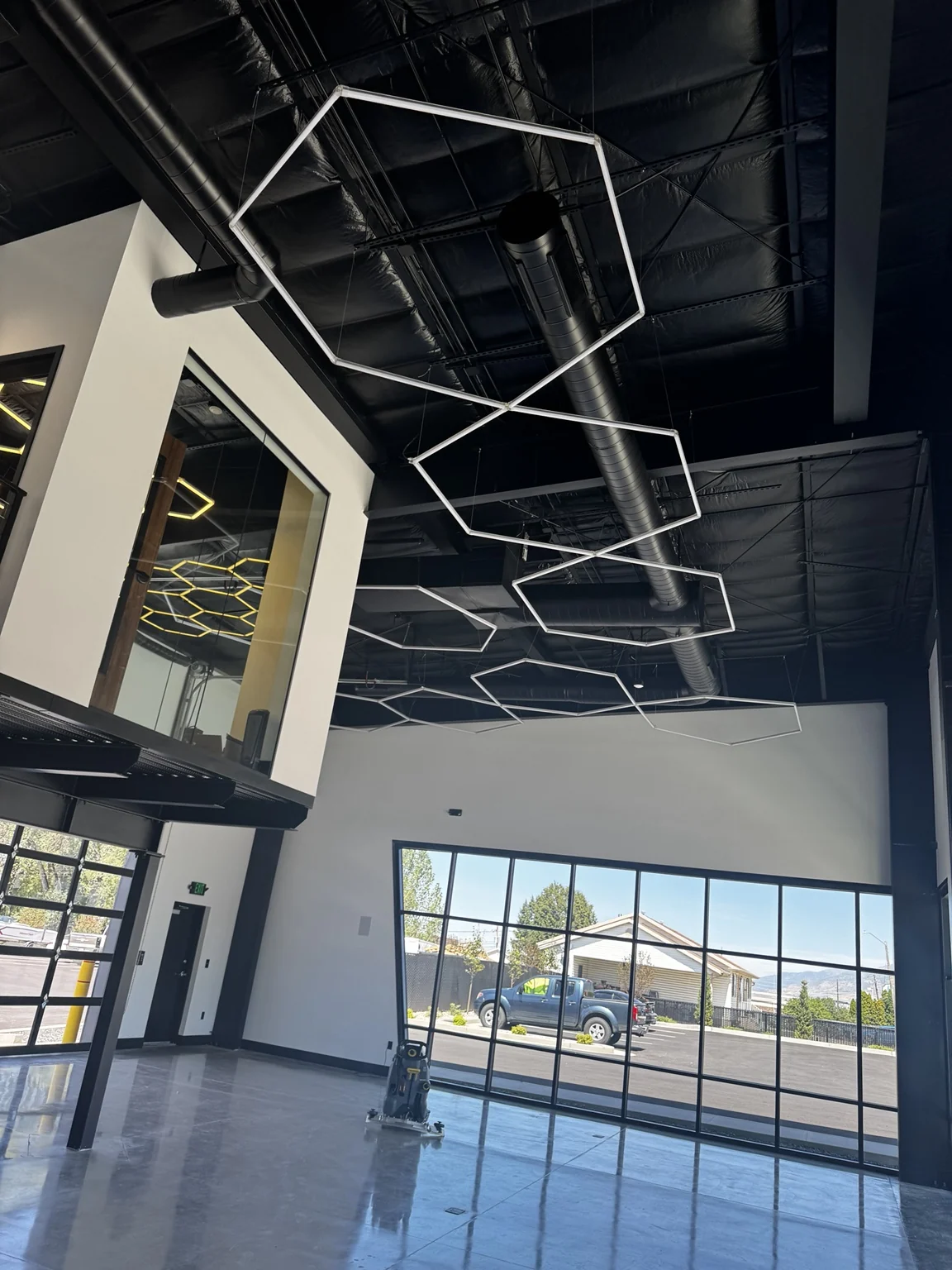 Completed marine showroom with a reflective floor coating, high-contrast painted interior, black architectural ceiling, and large glass storefront