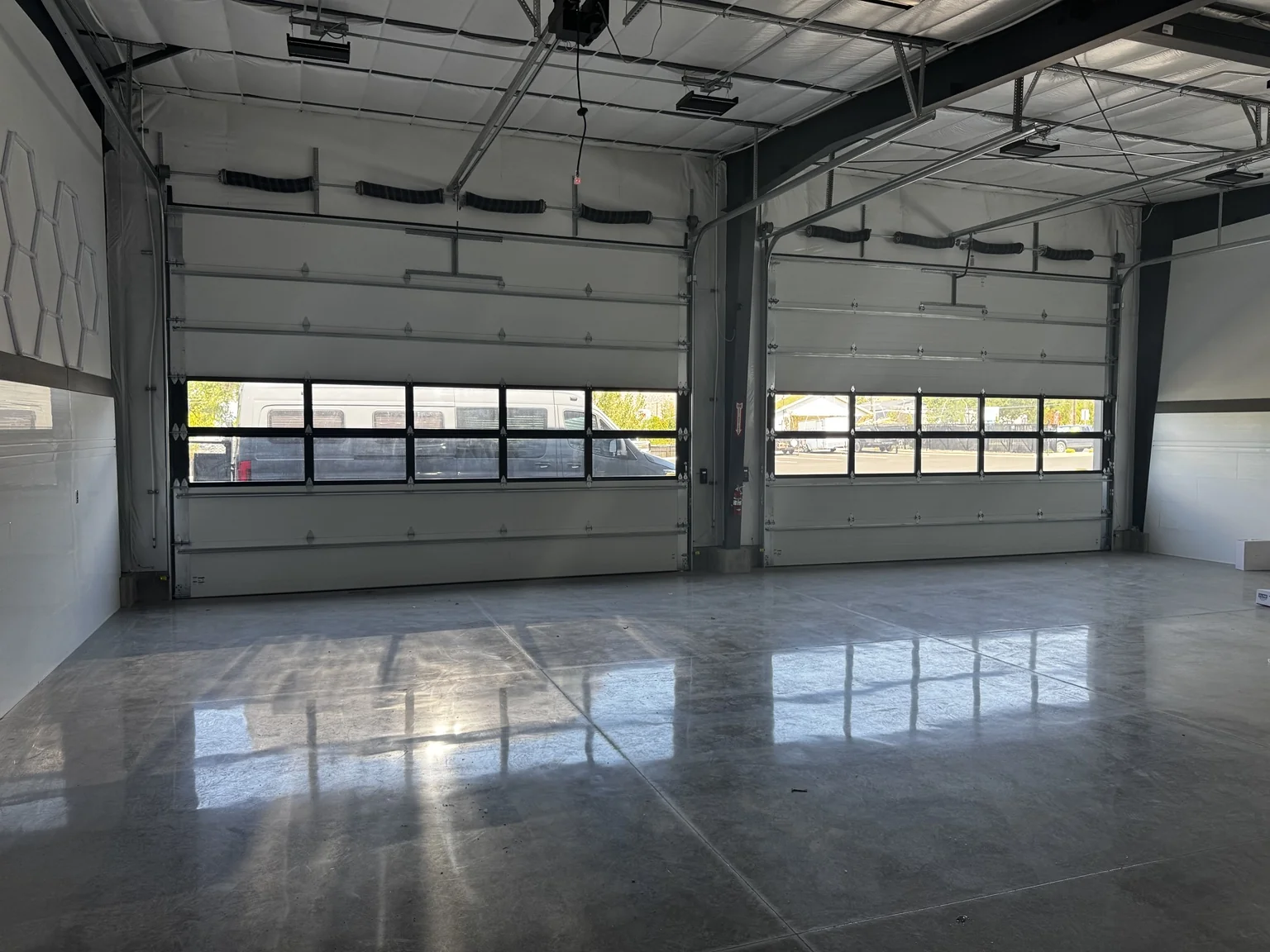 Boat-shop garage bay with two overhead doors and a reflective polished floor