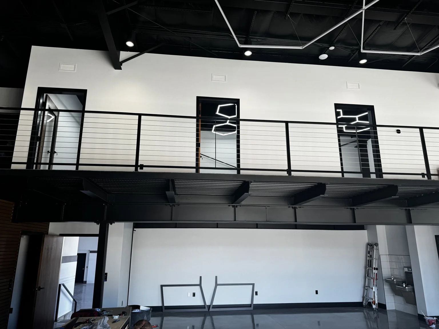 Boat-shop mezzanine with black steel framing, cable railing, and white office walls