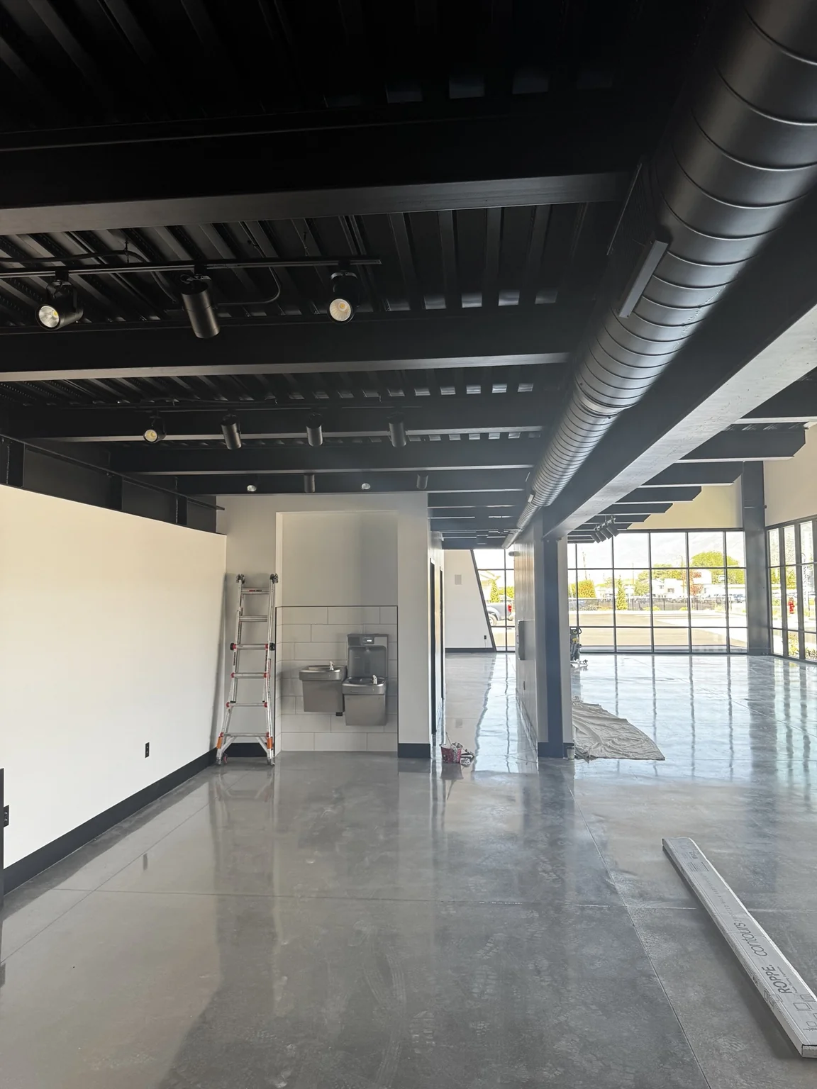 Long boat-shop showroom view showing a black exposed ceiling and reflective polished concrete floor