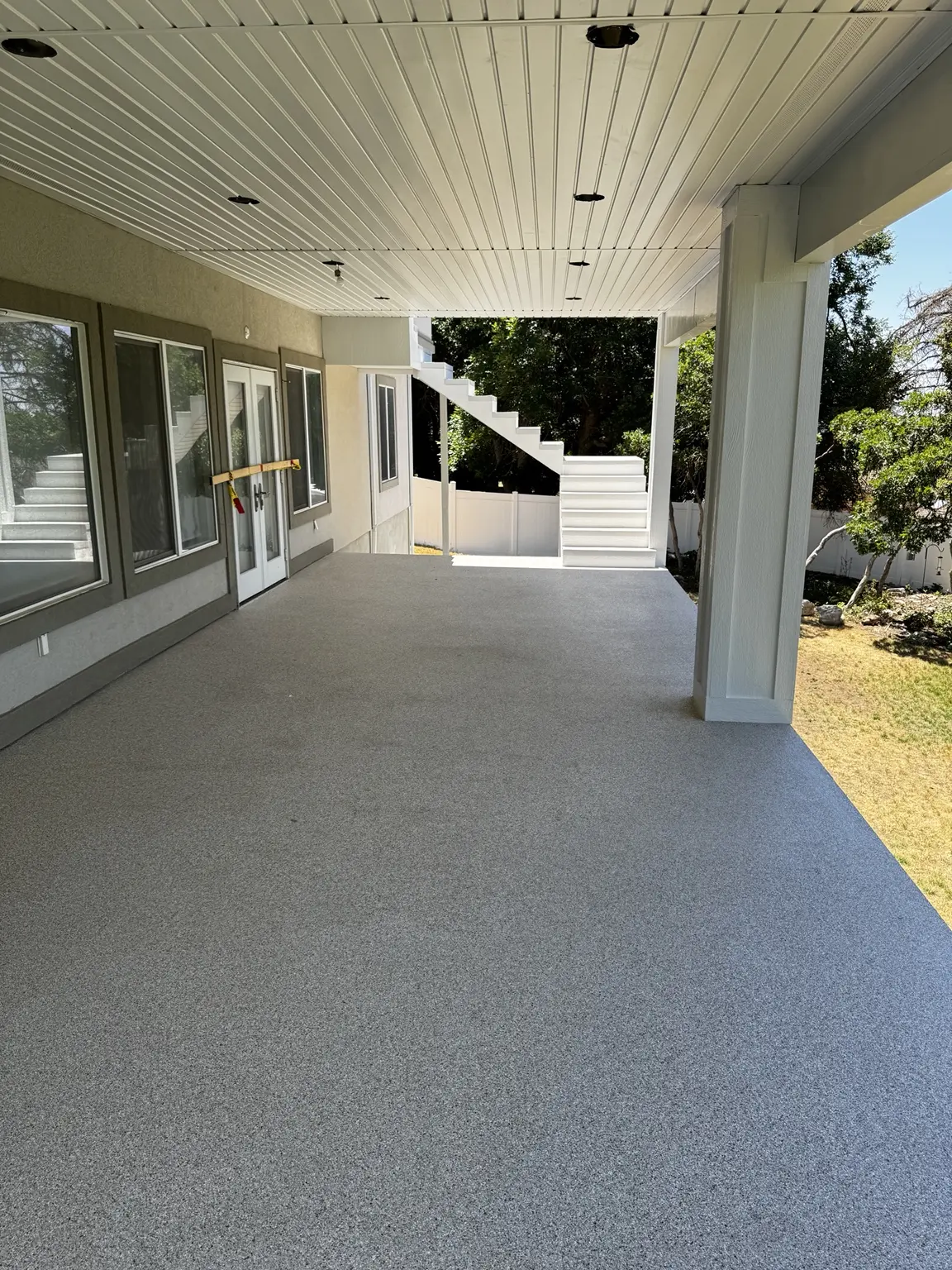 Covered residential deck with a completed light-gray waterproof coating in Bountiful, Utah